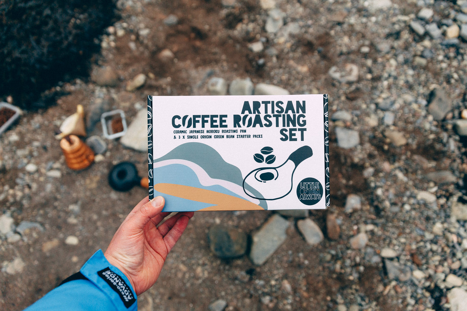 Hand holding a 'Artisan Coffee Roasting Set' package against a natural background.