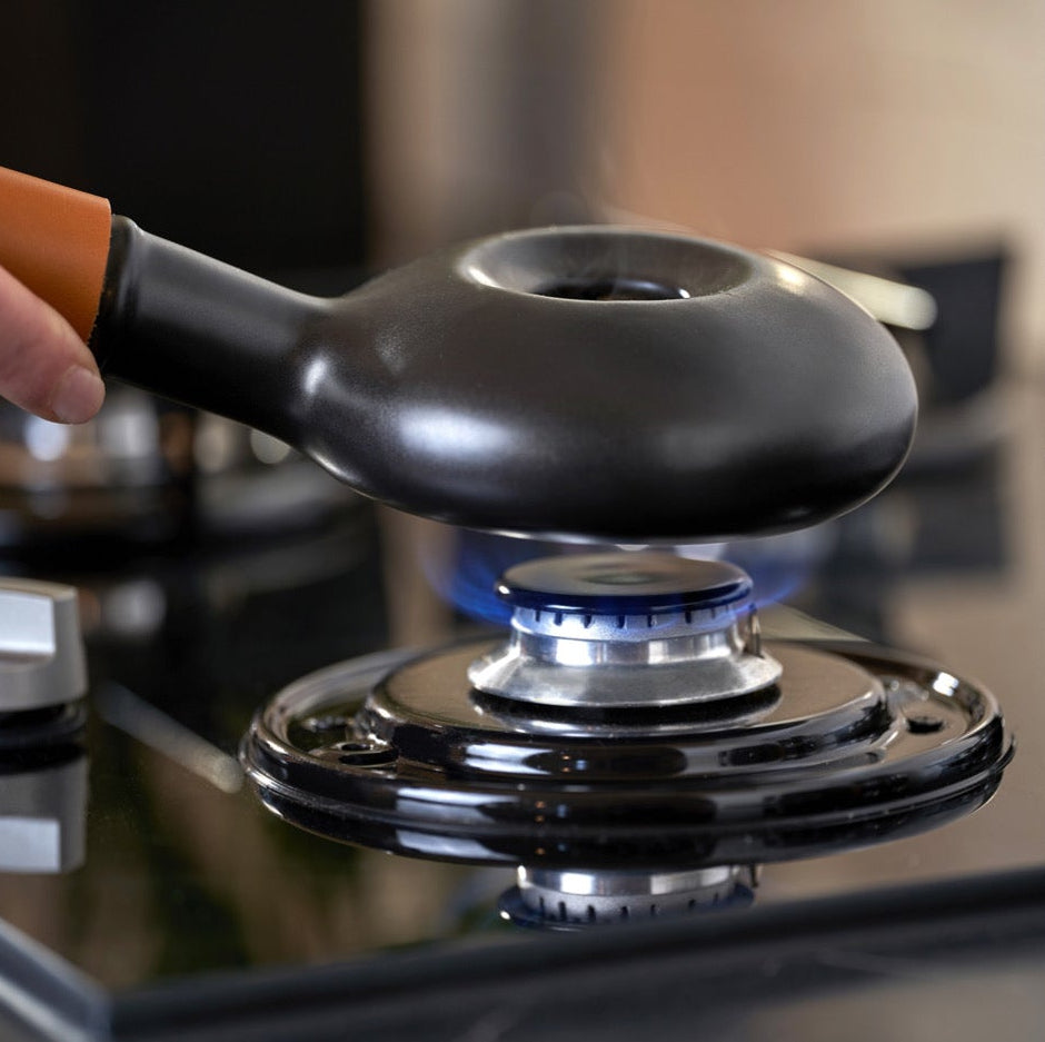 Hand holding a black coffee filter over a coffee machine with a blurred background